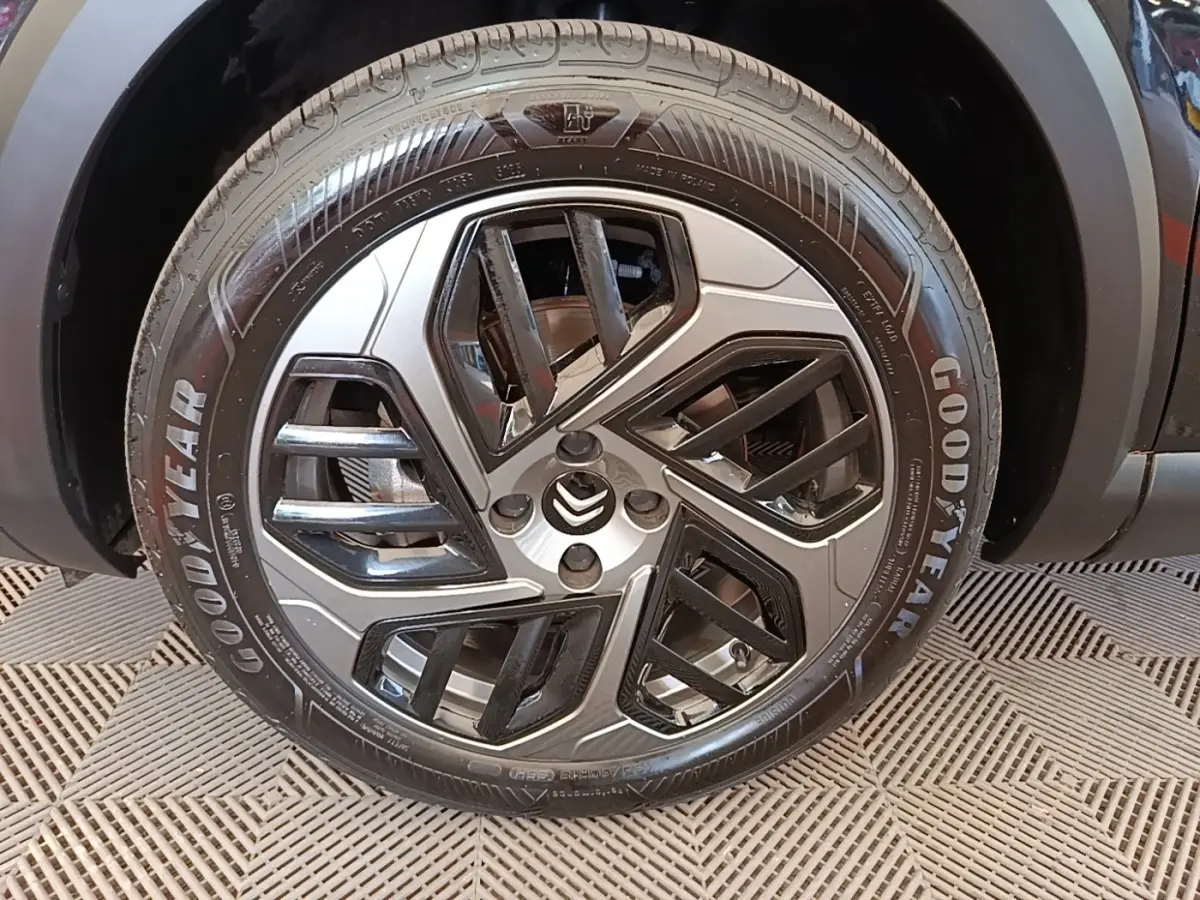 Gros plan sur la roue avant gauche noire avec jante alliage bicolore et pneu Goodyear d'une Citroën C4 X 2023.