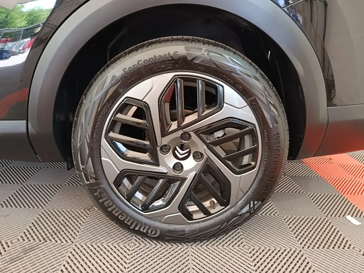 Gros plan sur la roue avant droite noire d'une Citroën C4 X 2023 avec jante alliage au design moderne.