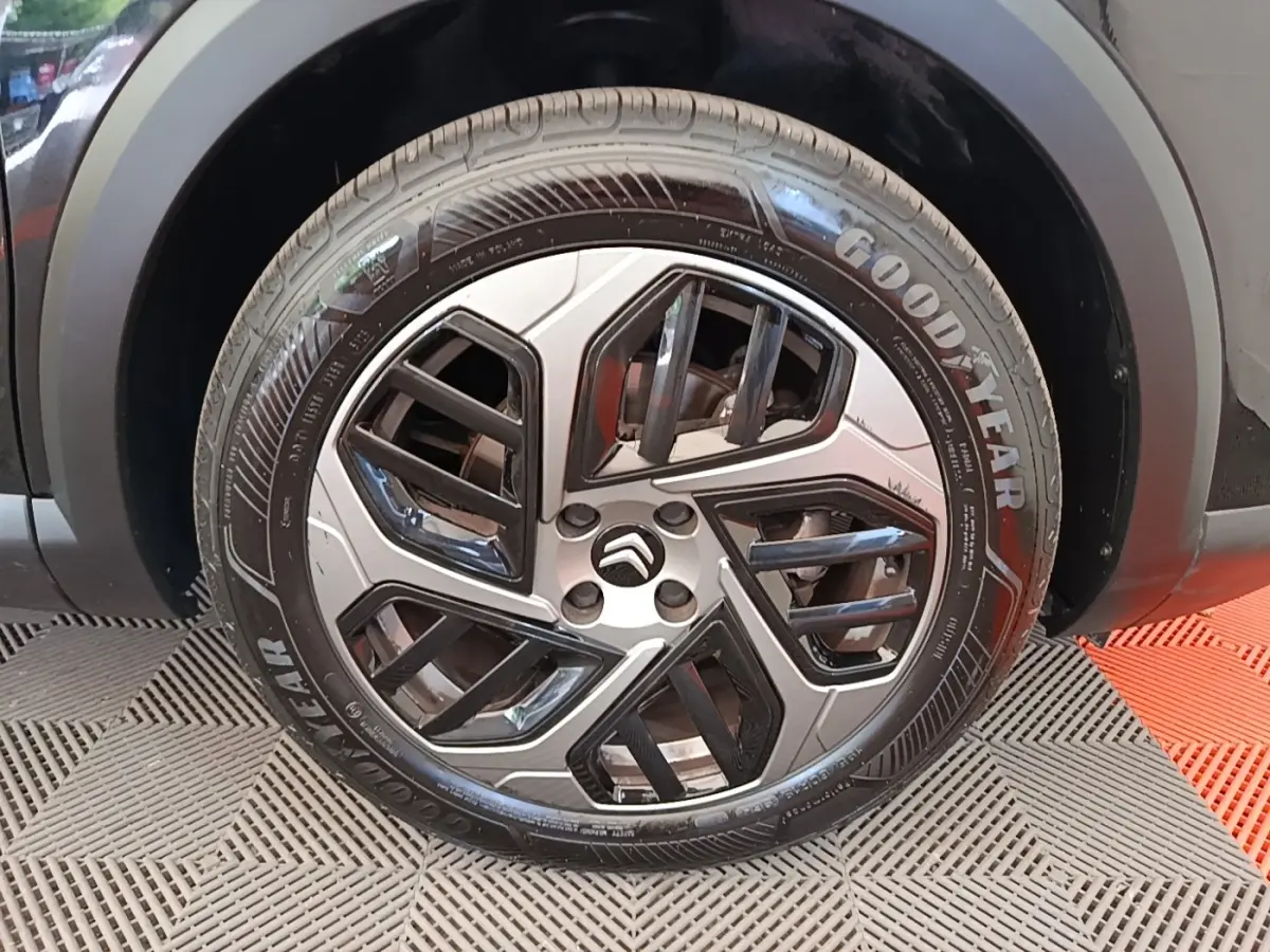 Gros plan sur la roue avant droite d'une Citroën C4 X noire, jante alliage au design géométrique bicolore.