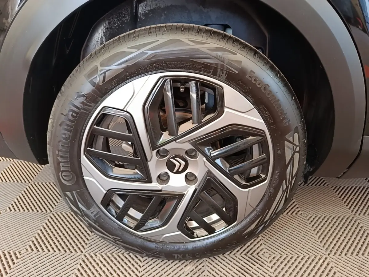 Gros plan sur la roue avant droite d’une Citroën C4 X noire, mettant en valeur la jante alliage au design géométrique.