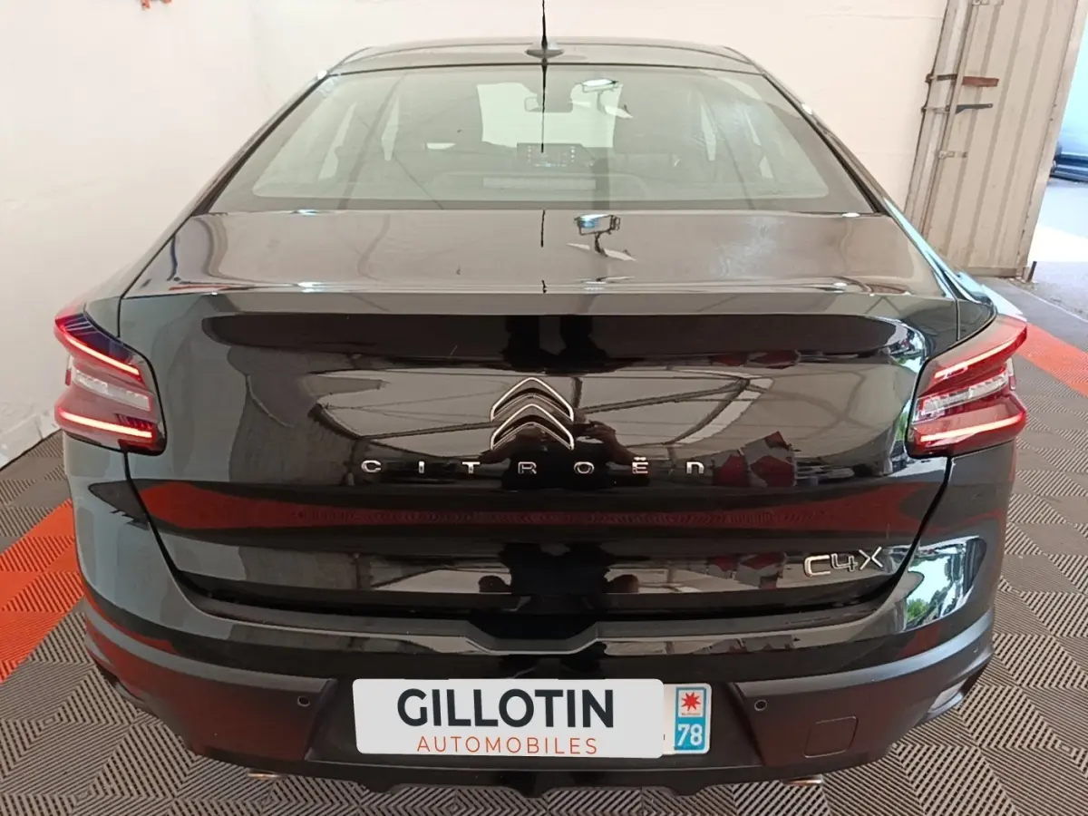 Vue arrière d'une Citroën C4 X noire 2023 avec feux LED et spoiler de coffre visible en intérieur.