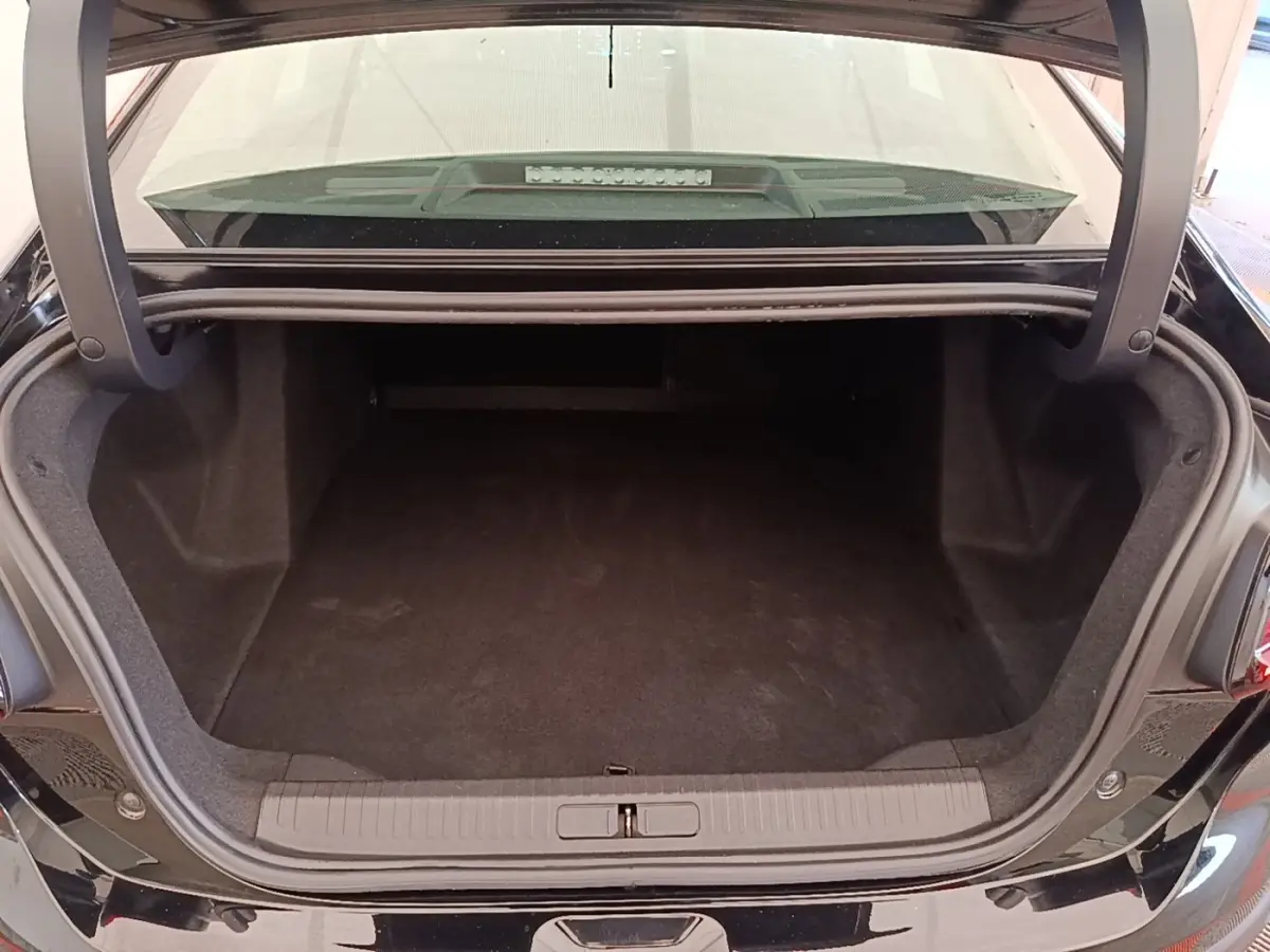 Coffre ouvert de la Citroën C4 X noire, vue arrière montrant l’espace de chargement vide et le seuil de coffre.