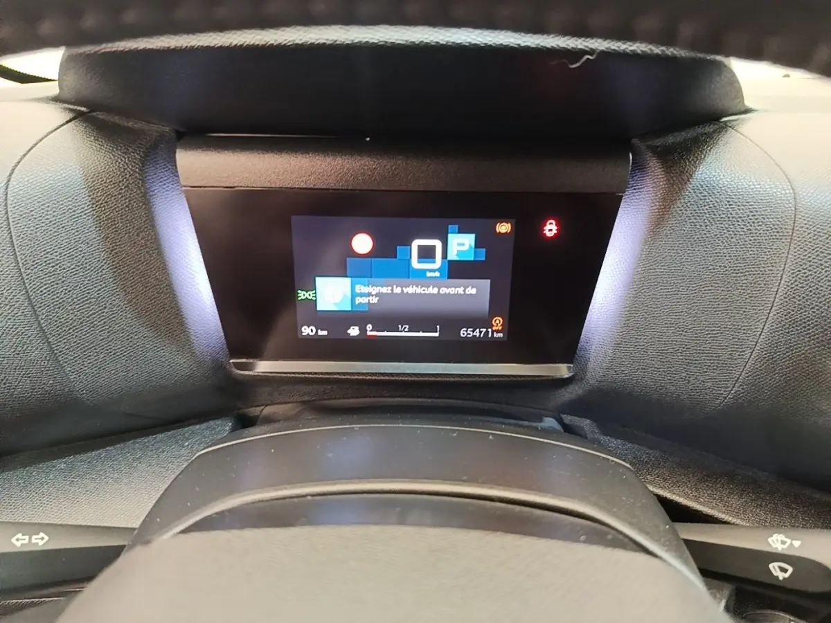 Vue rapprochée du tableau de bord numérique de la Citroën C4 X noire, affichant un message d'alerte au stationnement.