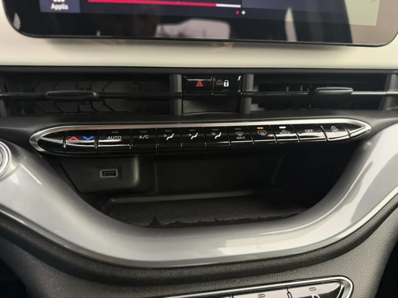 Vue rapprochée de la console centrale de la Fiat 500 électrique blanche, mettant en valeur les commandes de climatisation et l'écran tactile.