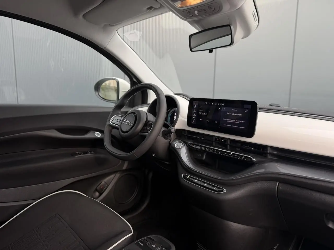 Intérieur avant droit de la Fiat 500 électrique blanche 2024, avec tableau de bord moderne et écran tactile horizontal.
