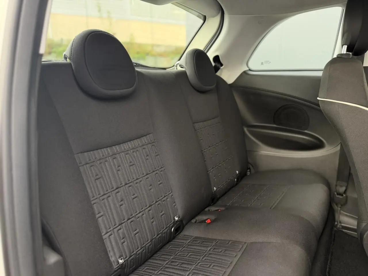 Vue intérieure côté arrière droit montrant les sièges arrière noirs avec motifs FIAT embossés sur la banquette.