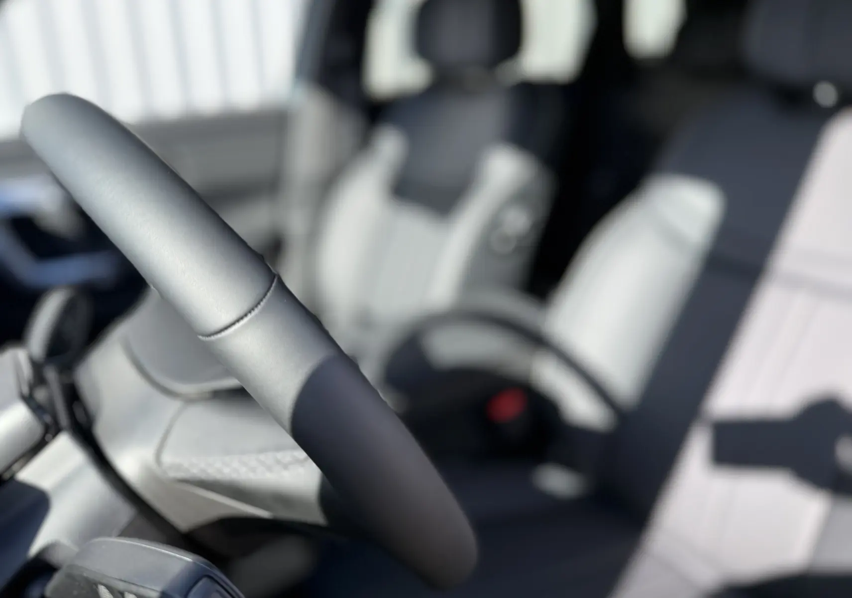Gros plan sur le volant et siège avant gris clair de la JAECOO J7 PHEV 279 CH SHS-P EXCLUSIVE, intérieur lumineux.