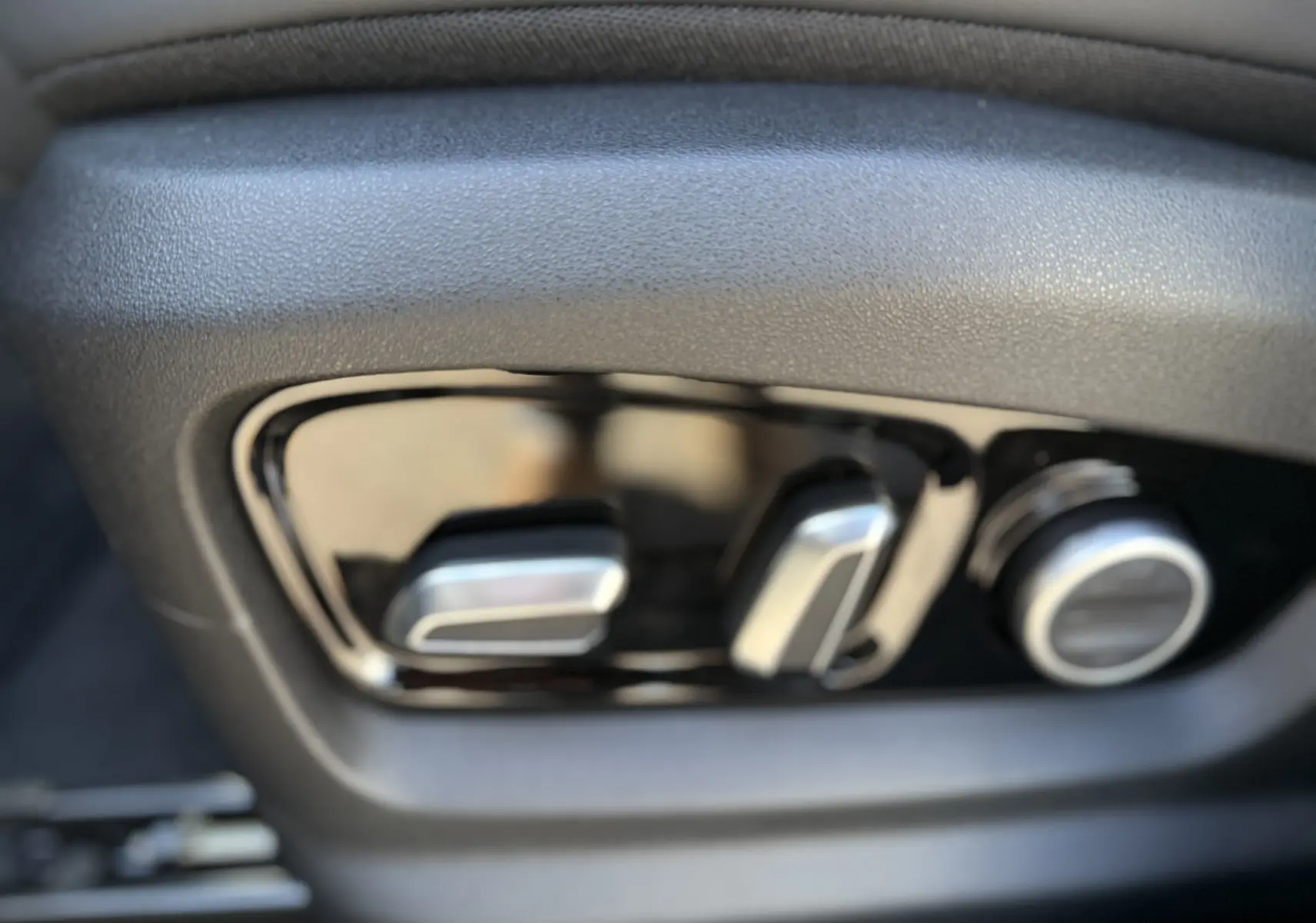 Gros plan sur les commandes de réglage électrique du siège avant dans l'habitacle du JAECOO J7 PHEV argent Moonlight.