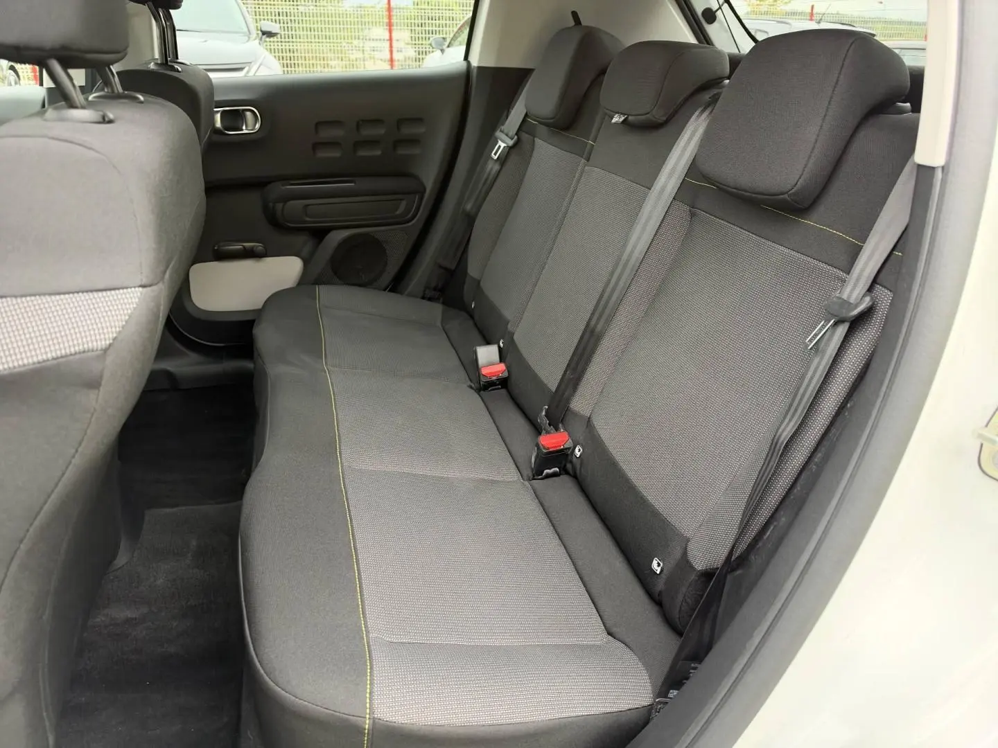 Vue intérieure côté droit de la banquette arrière en tissu gris avec surpiqûres jaunes d'une Citroën C3 Blanc Banquise 2024.