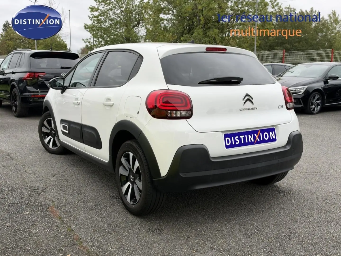 Citroën C3 blanc Banquise vue 3/4 arrière droit avec jantes alu et protections noires sur parking.