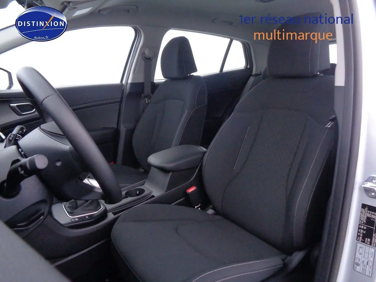 Vue intérieure côté conducteur du Kia Sportage gris acier 2022, sièges noirs avec coutures contrastées et console centrale.