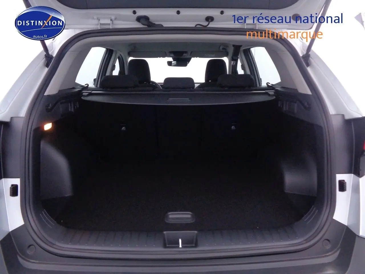 Coffre ouvert vu de l'arrière d'un Kia Sportage gris acier métal, montrant l'espace de chargement vide.