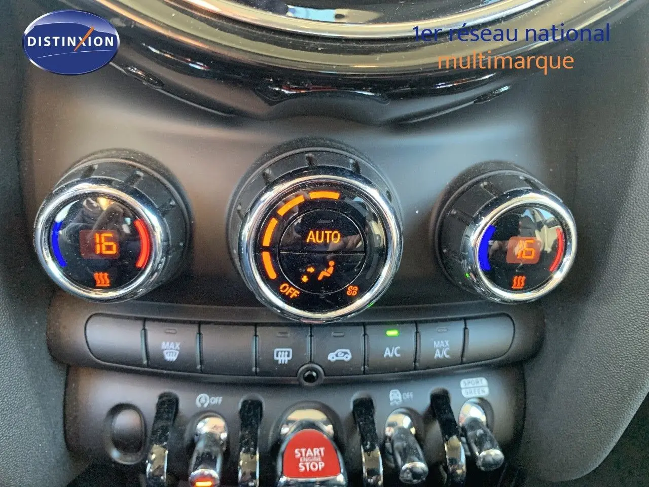 Gros plan sur les commandes de climatisation automatique du MINI rouge chili, avec affichage numérique et boutons chromés.