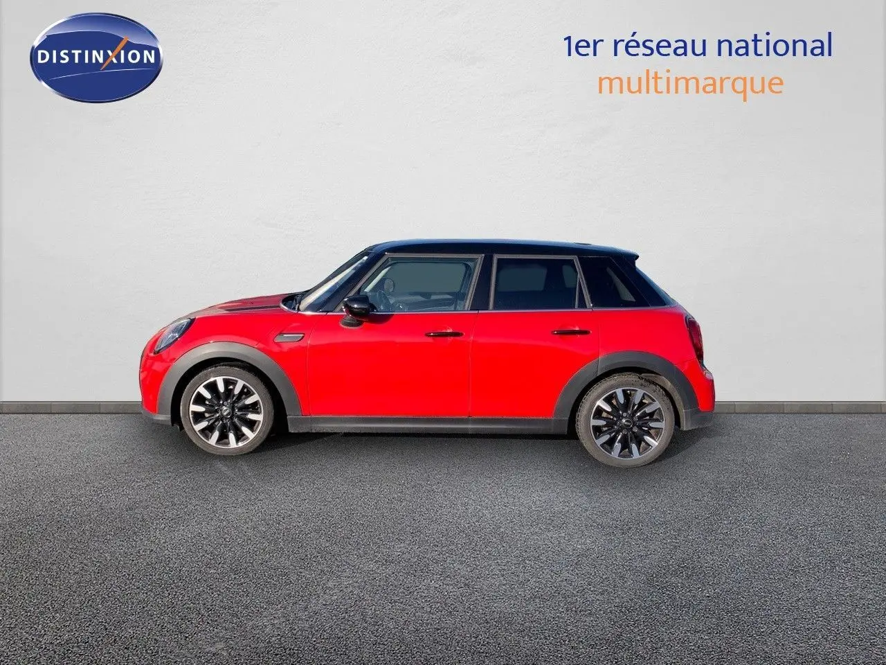 Profil côté gauche d'une MINI 5 portes rouge chili avec toit noir et jantes alliage noires sur fond neutre.