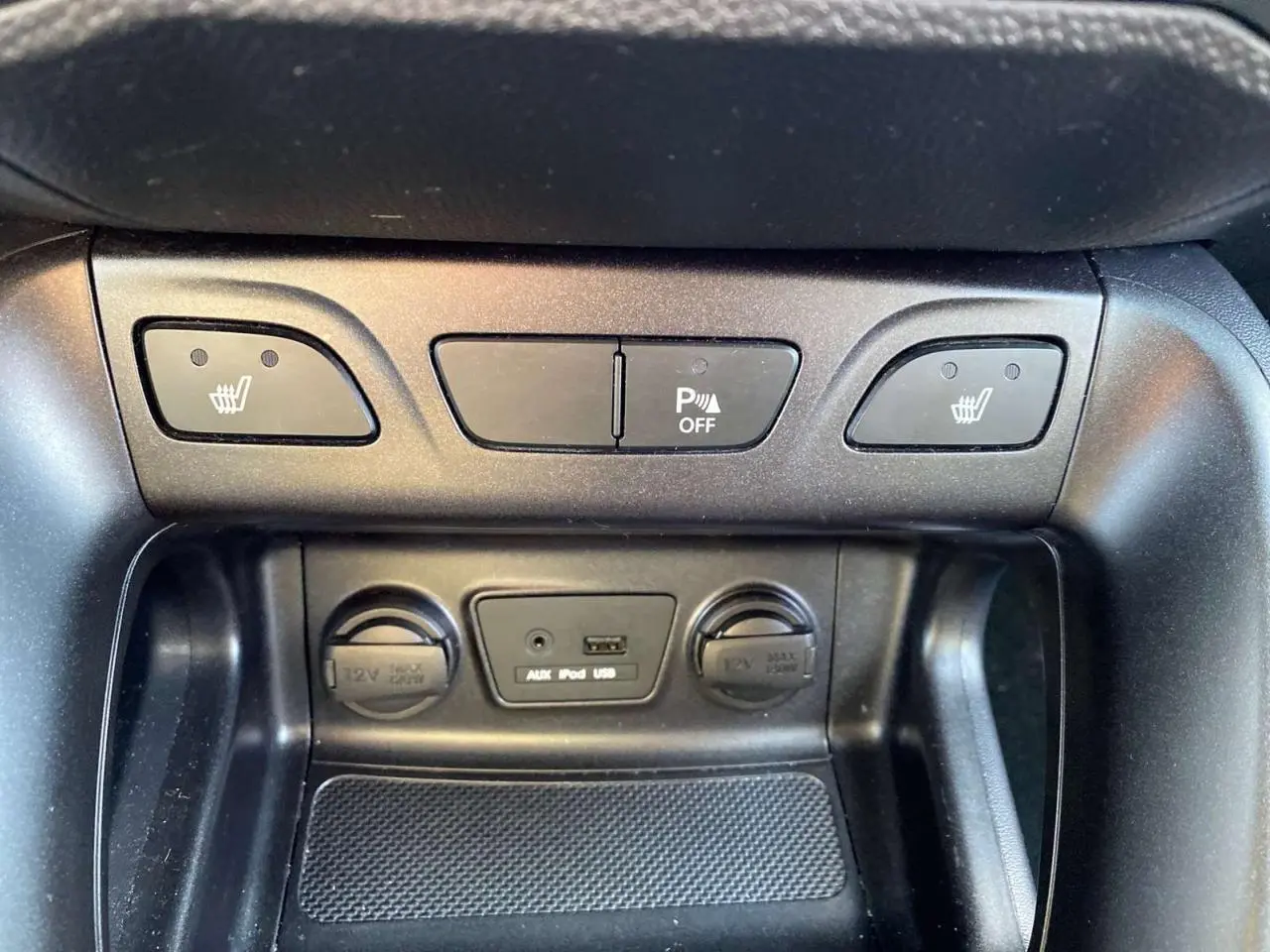 Détail de la console centrale du Hyundai ix35 blanc 2014 montrant les commandes des sièges chauffants et prises 12V, USB, AUX.