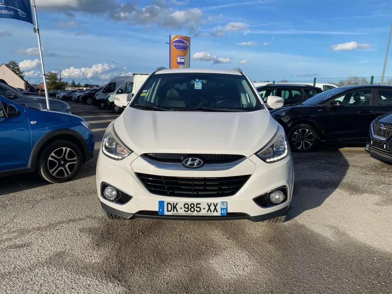 Vue de face d'un Hyundai ix35 blanc stationné, avec ses projecteurs et calandre distinctifs visibles.