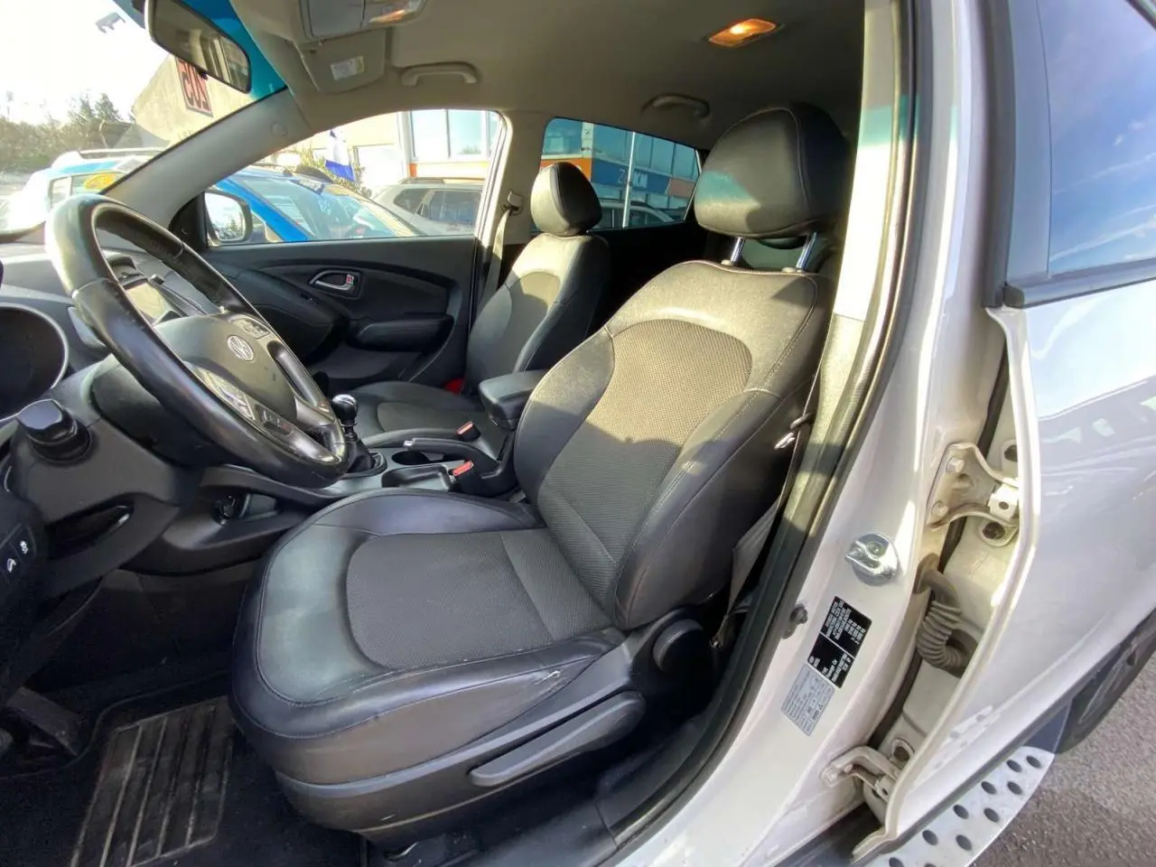 Intérieur avant droit du Hyundai ix35 blanc 2014, sièges tissu-cuir et volant avec commandes intégrées.