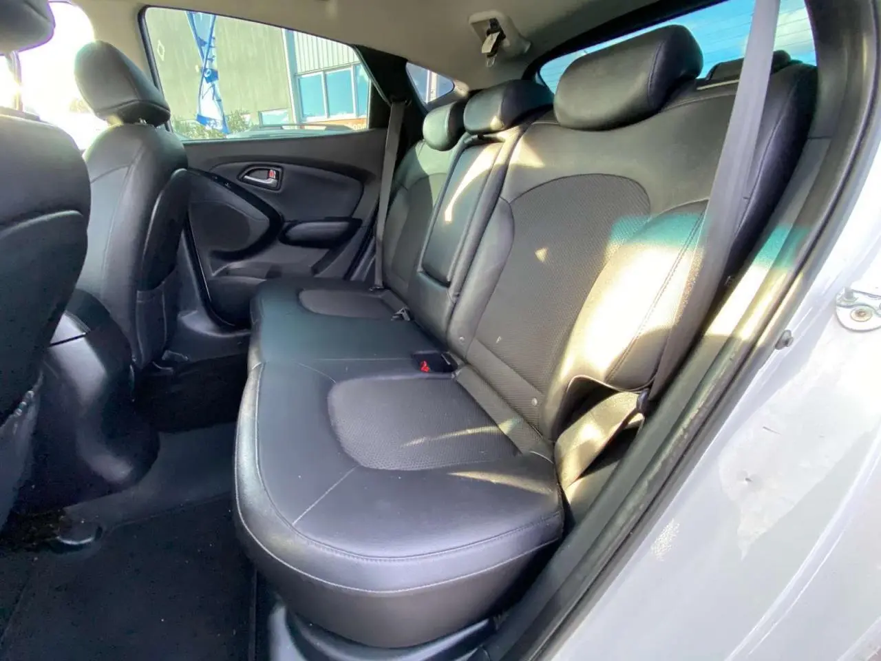 Vue intérieure côté arrière droit montrant la banquette en cuir noir du Hyundai ix35 blanc de 2014.