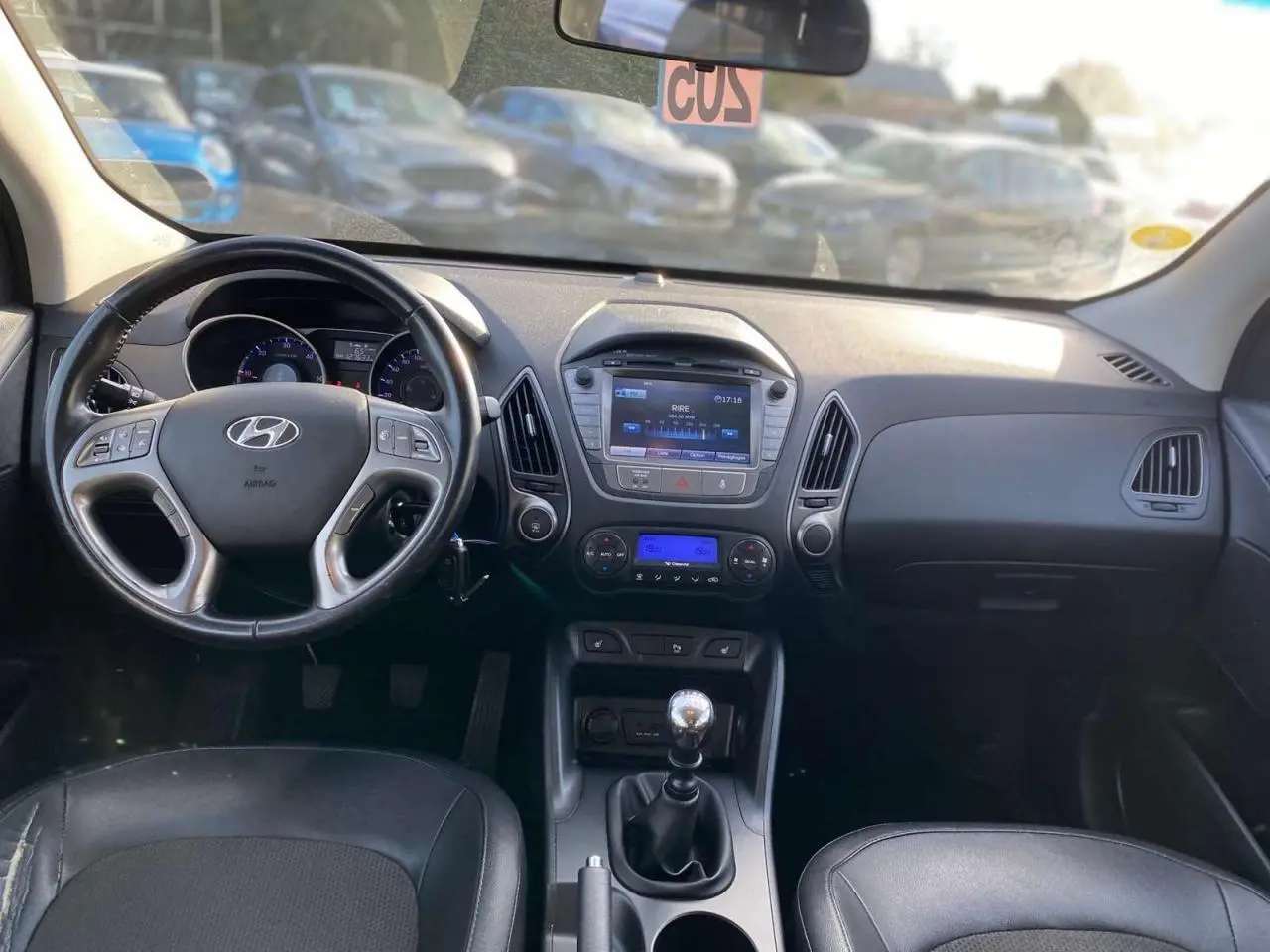 Intérieur du Hyundai ix35 blanc 2014, vue frontale du tableau de bord avec volant, écran tactile et levier de vitesse manuel.