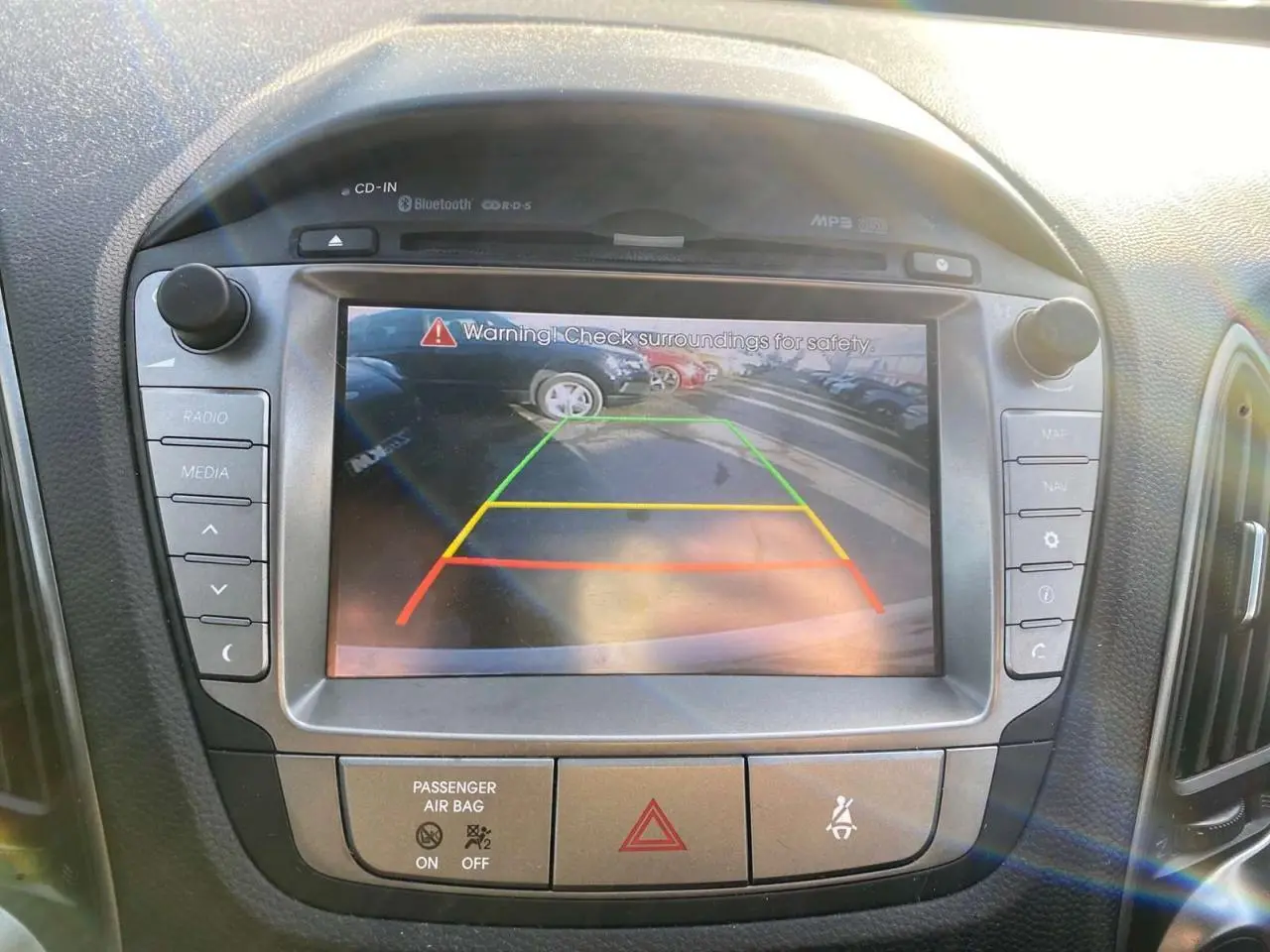 Écran tactile central du Hyundai ix35 blanc de 2014 montrant l'image de la caméra de recul avec repères colorés.