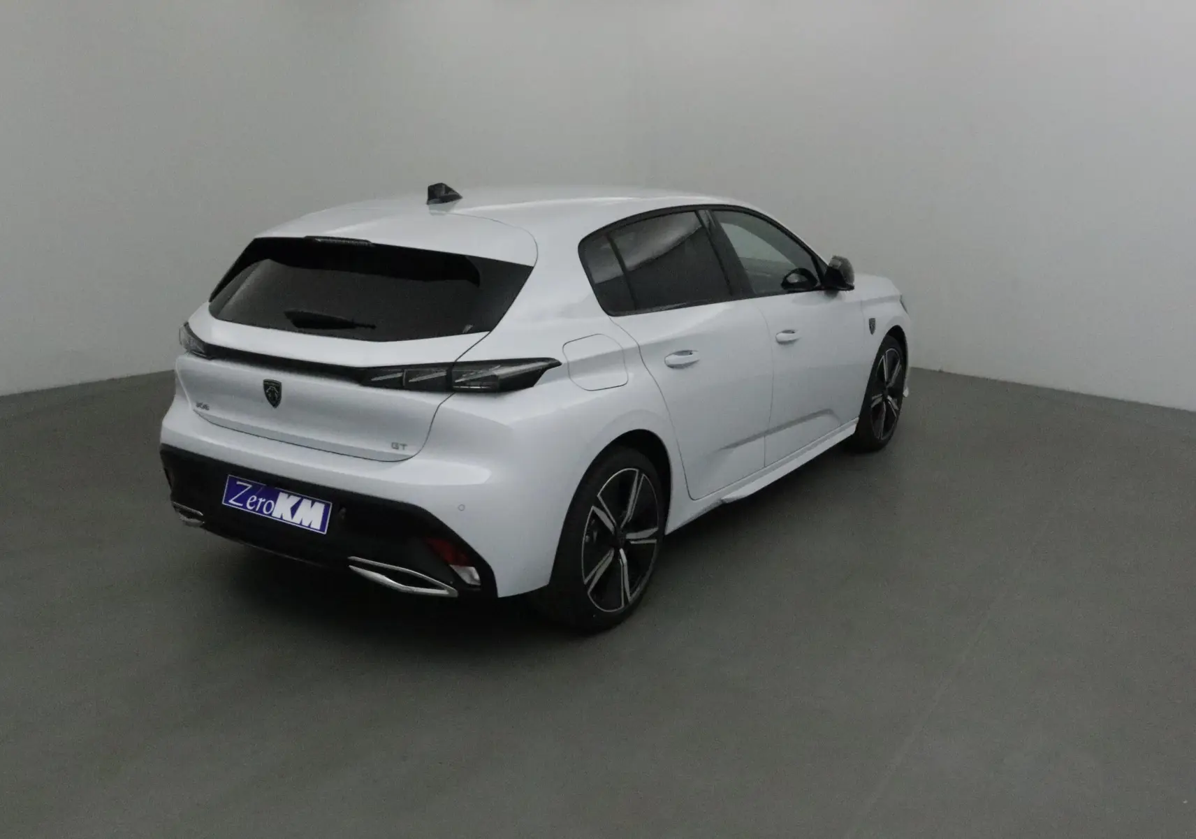 Peugeot 308 GT+Pack Vision 360 blanc Okenite vue 3/4 arrière droit avec jantes alliage et vitres teintées.