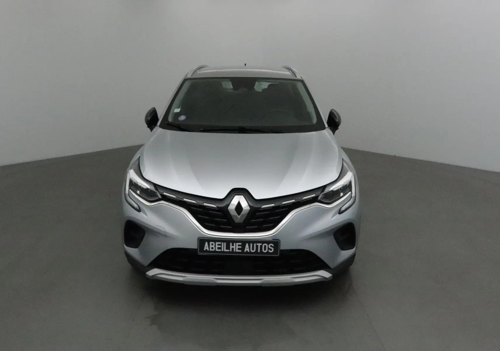 Vue frontale d'un Renault Captur gris Highland 2020 avec calandre noire et logo Renault bien visible.