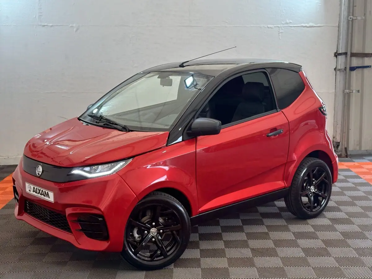 Vue 3/4 avant droite d'une Aixam Ambition 0.5 City Sport rouge avec toit noir et jantes noires brillantes.
