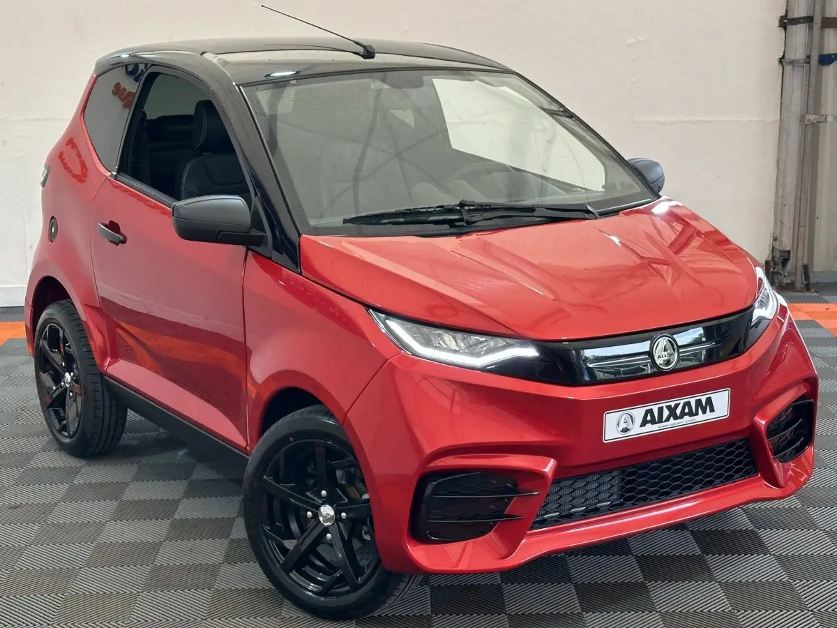 Vue 3/4 avant d'une Aixam Ambition 0.5 City Sport rouge avec toit noir et jantes noires, rétroviseur caméra côté gauche.