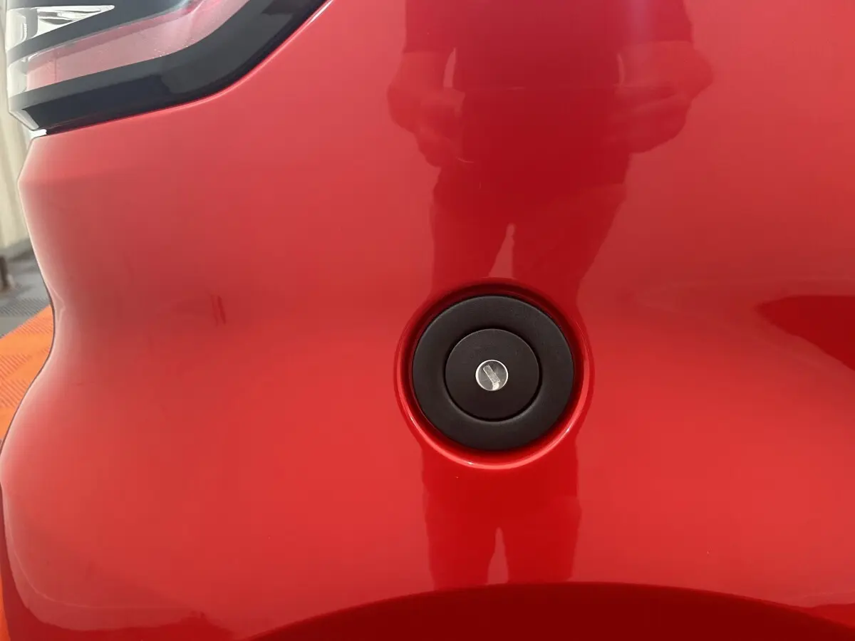 Détail du bouchon de réservoir noir sur la carrosserie rouge de l'AIXAM AMBITION 0.5 CITY SPORT, vue rapprochée.