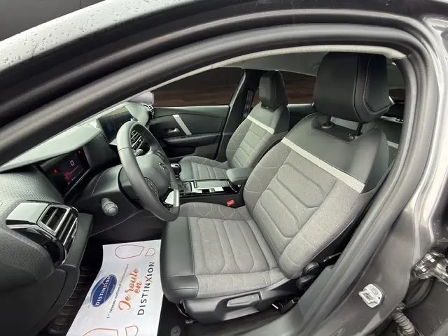 Vue intérieure côté conducteur de la Citroën C4 gris platinium 2022, sièges tissu gris clair avec appuie-têtes noirs.