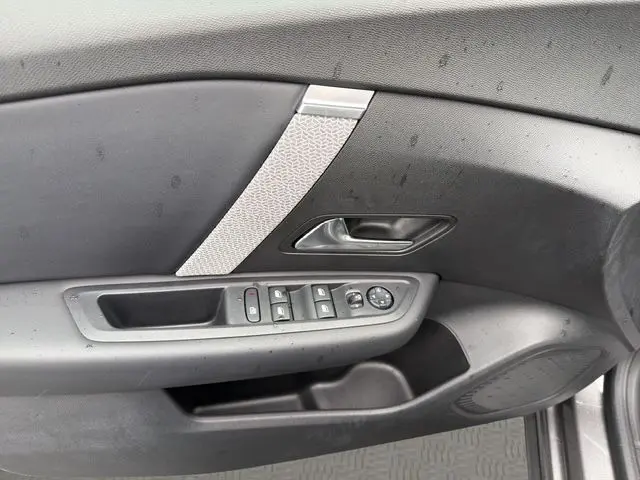 Vue rapprochée de la porte côté conducteur de la Citroën C4 gris platinium avec commandes électriques et poignée argentée.