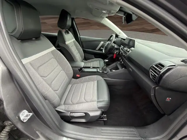 Vue intérieure côté conducteur de la Citroën C4 1.5 BlueHDi 110 Feel Pack 2022 avec sièges tissu gris et tableau de bord moderne.