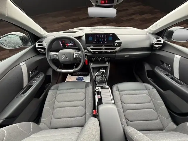 Vue intérieure avant de la Citroën C4 1.5 BlueHDi 110 Feel Pack 2022, avec tableau de bord moderne et sièges gris tissu.