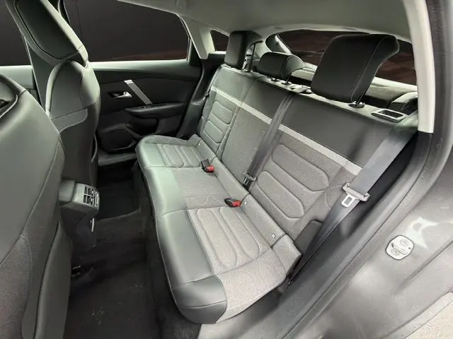 Vue intérieure arrière côté droit de la Citroën C4 gris platinium, montrant les sièges arrière en tissu gris et cuir noir.