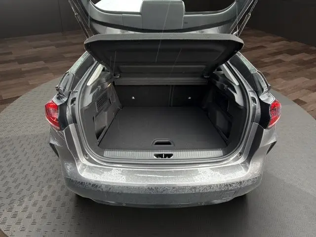 Vue arrière ouverte du coffre d'une Citroën C4 gris platinium 2022, montrant un espace de chargement propre et spacieux.