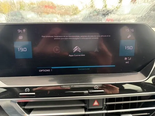 Écran tactile central du tableau de bord de la Citroën C4 2022, affichant la température et les options connectées.