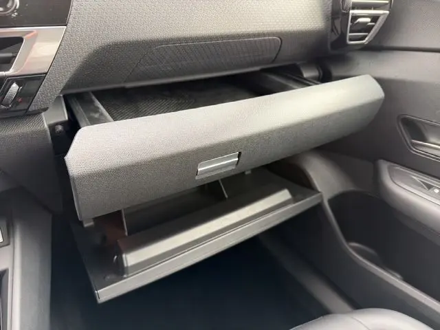 Vue intérieure côté passager de la boîte à gants ouverte du Citroën C4 gris platinium, montrant la texture du tableau de bord.