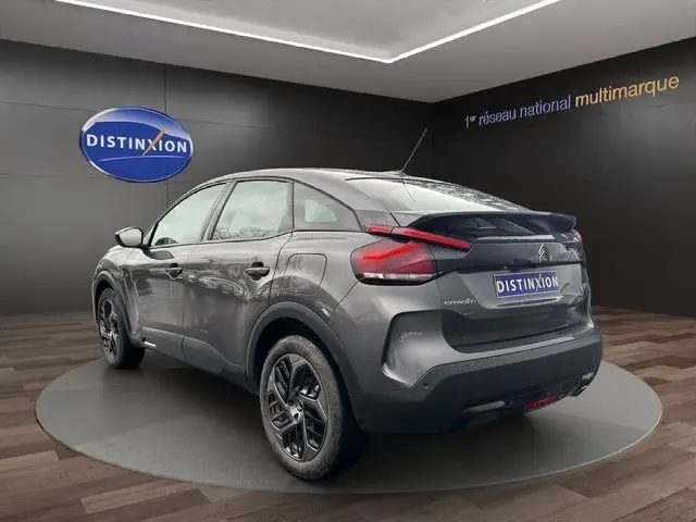 Vue 3/4 arrière droite d'une Citroën C4 1.5 BlueHDi 110 Feel Pack gris platinium, avec jantes alliage et feux LED distinctifs.