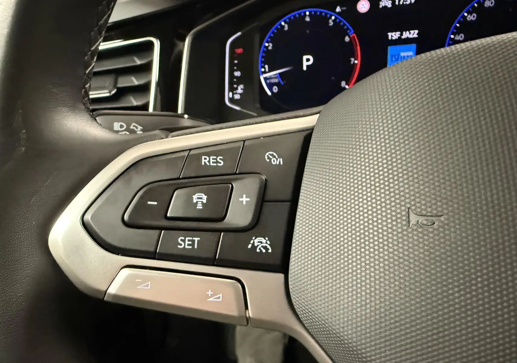 Gros plan sur les commandes au volant à gauche du Volkswagen Taigo 1.5 TSI 150 DSG7 R-Line Edition, tableau de bord numérique visible.