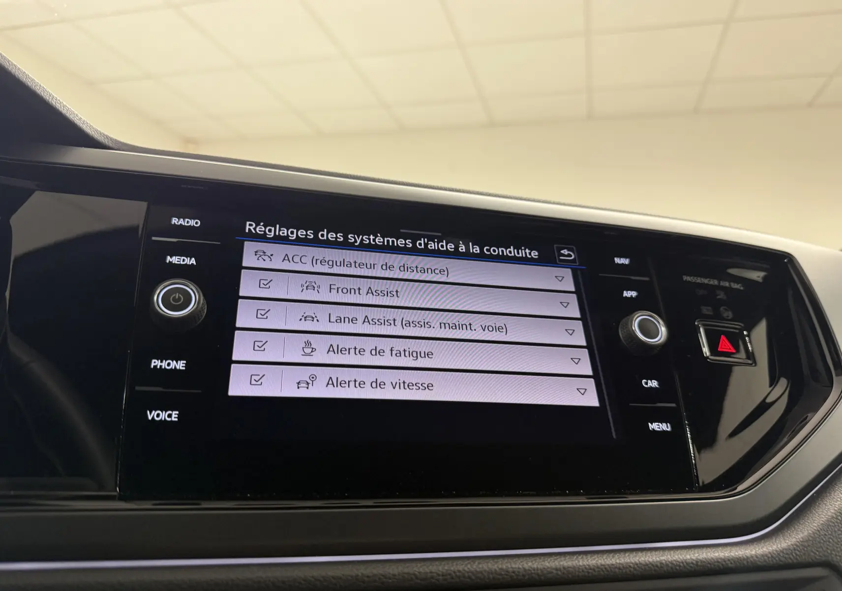 Écran tactile central du Volkswagen Taigo 2025 affichant les réglages des aides à la conduite, intérieur noir.