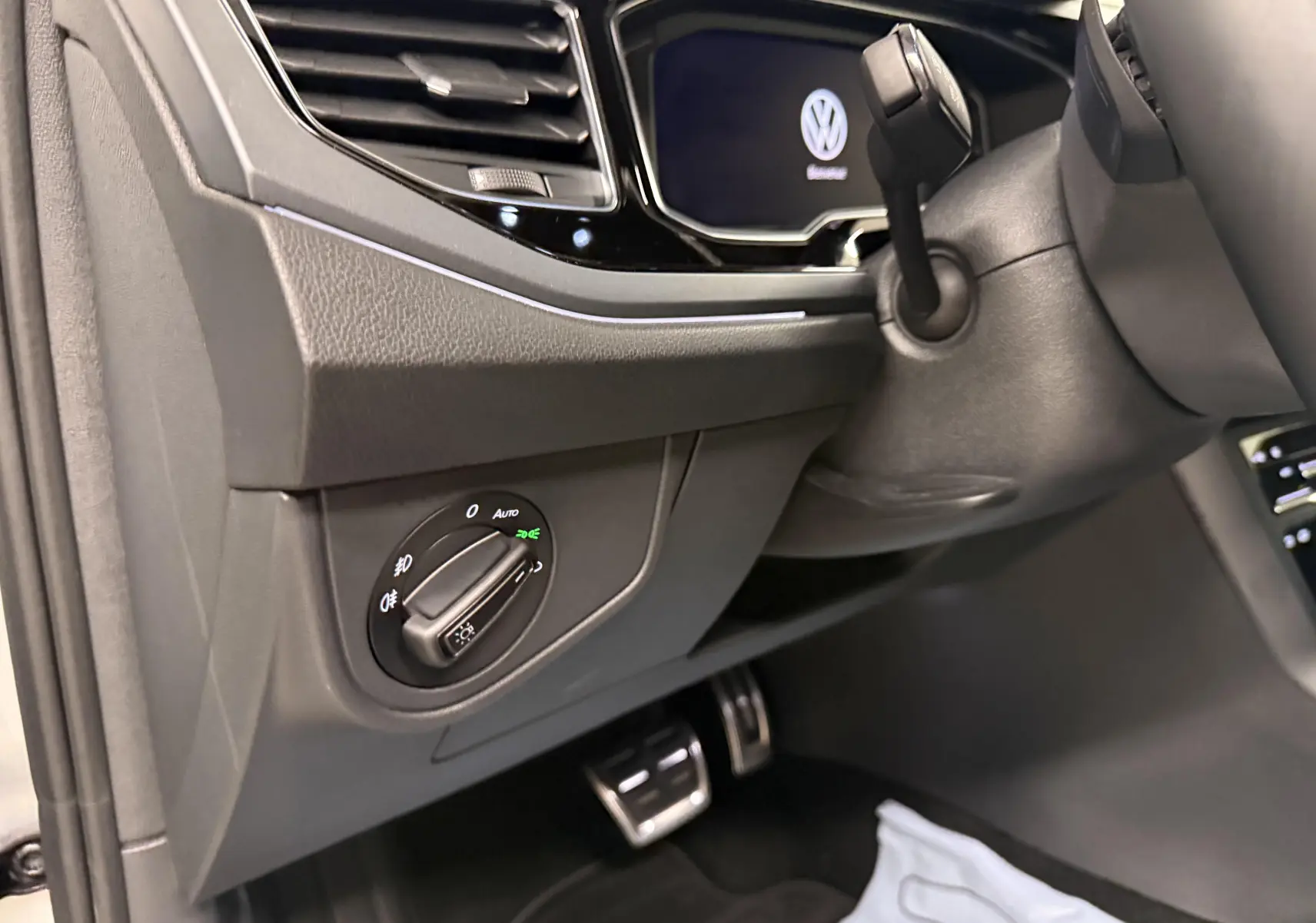 Gros plan sur le tableau de bord côté gauche du Volkswagen Taigo 2025, avec commandes d’éclairage et pédales en aluminium.