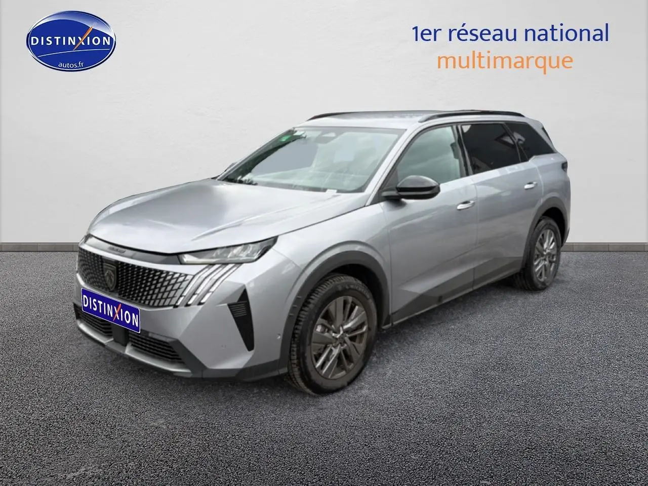 Peugeot 5008 gris artense en 3/4 avant droit, avec calandre distinctive et jantes alu visibles.