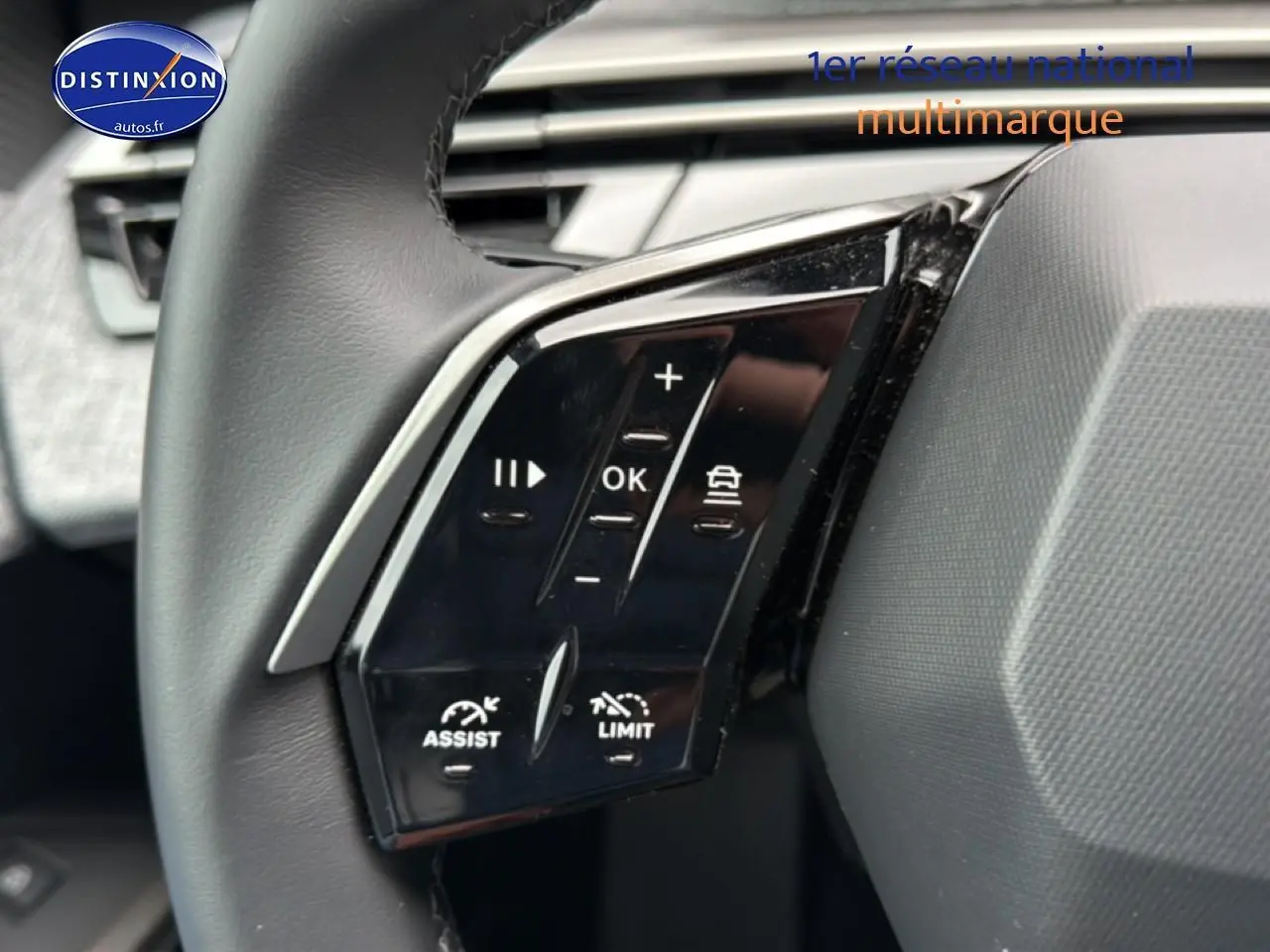 Gros plan sur les commandes multifonctions noires à gauche du volant cuir du Peugeot 5008 gris Artense 2025.