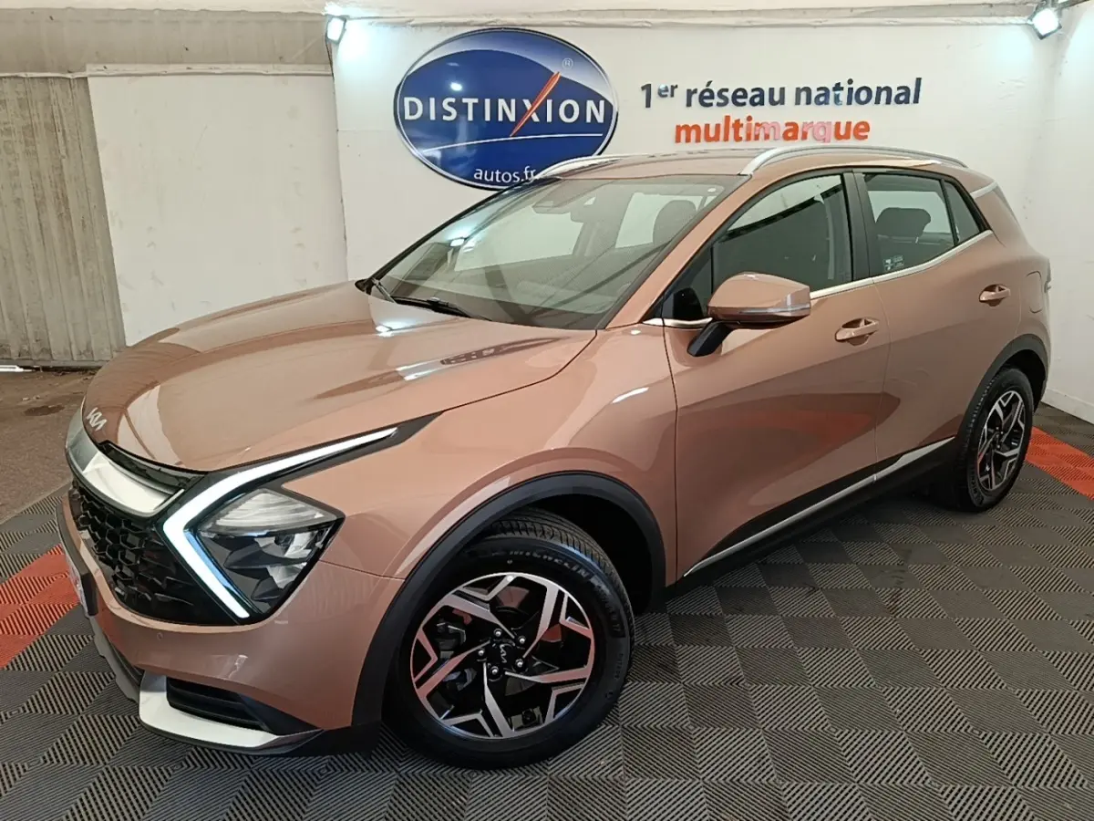 KIA Sportage beige vue 3/4 avant droit, avec phares LED en forme de flèche et jantes alliage distinctives.