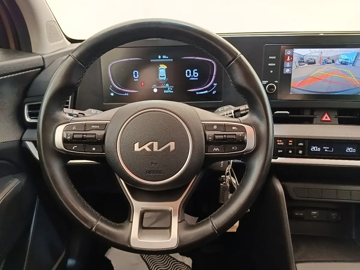 Vue frontale du volant en cuir noir du KIA SPORTAGE 2022 avec tableau de bord numérique et écran tactile de recul.