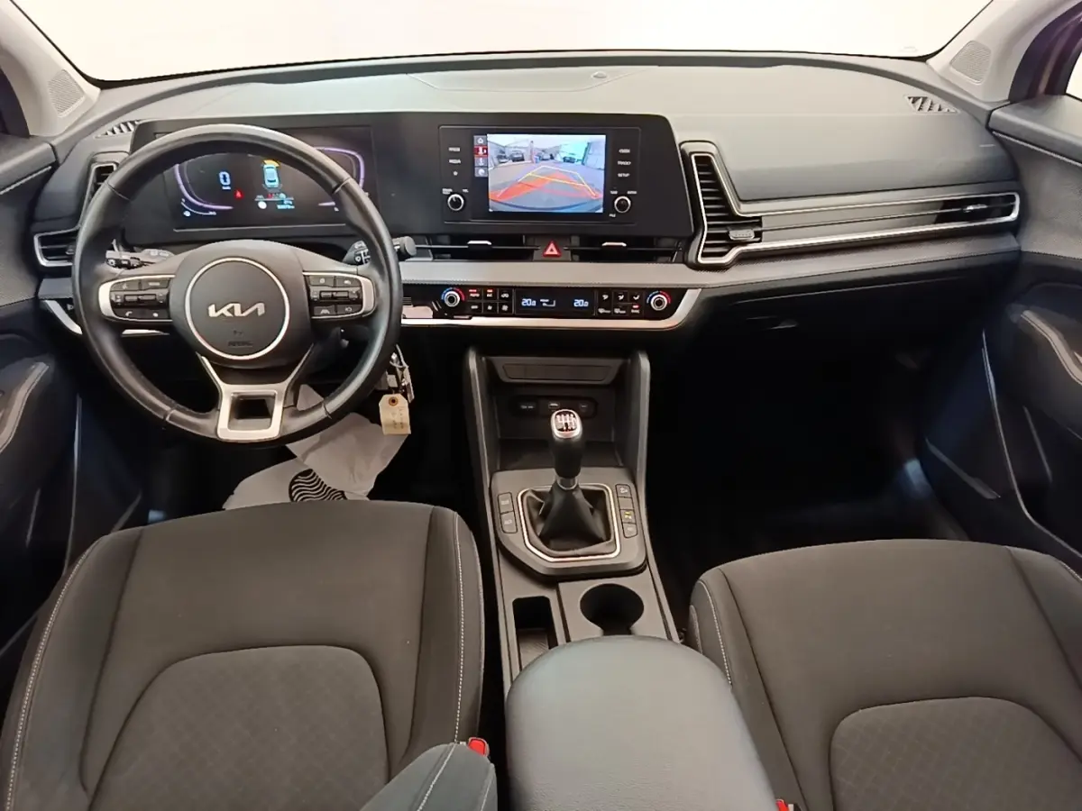Vue intérieure avant du Kia Sportage 2022 avec tableau de bord numérique et boîte manuelle noire.