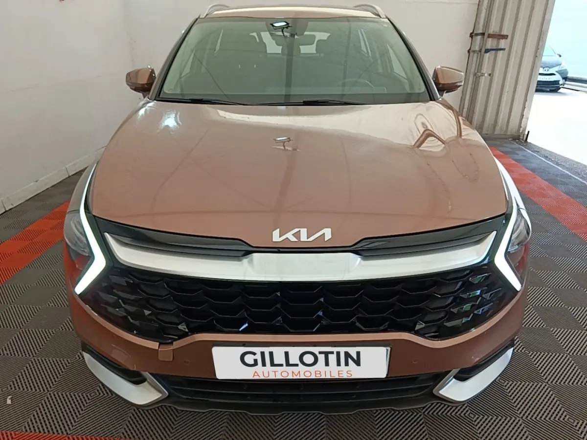 Vue avant d’un KIA Sportage beige 2022 avec calandre noire et feux diurnes LED en forme de V.