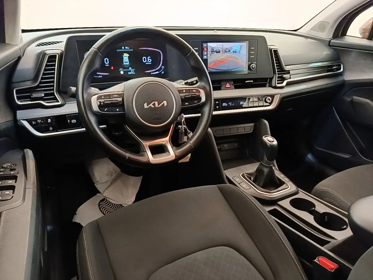 Vue intérieure du poste de conduite du Kia Sportage 2022 avec volant cuir multifonctions et écran tactile central affichant la caméra de recul.