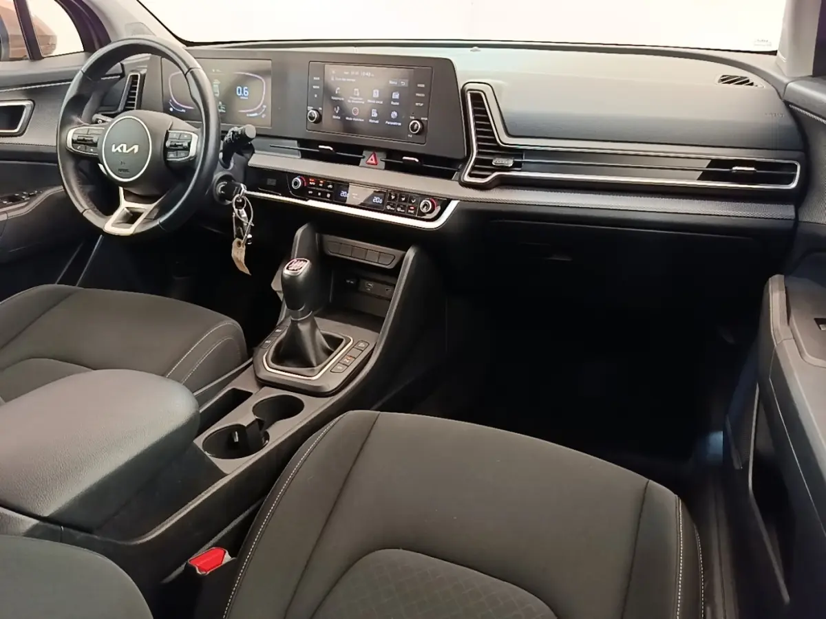Intérieur noir du Kia Sportage 2022 vu côté conducteur, avec volant cuir multifonctions et boîte manuelle.