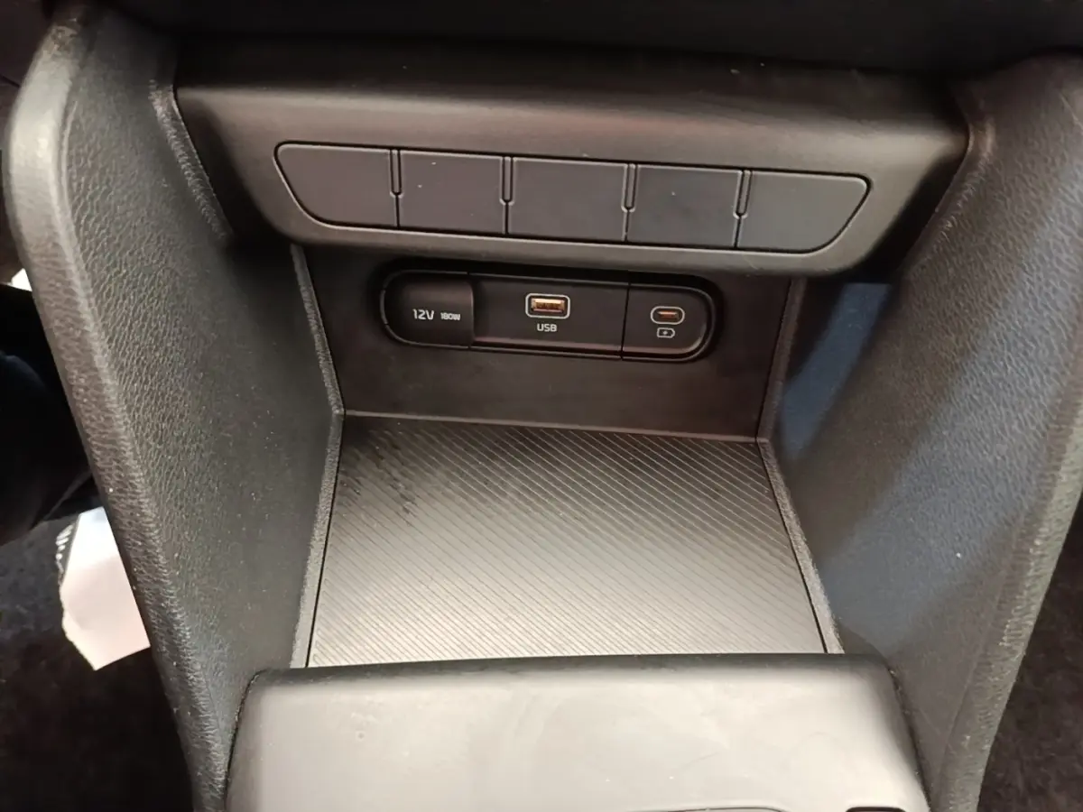 Vue rapprochée de la console centrale du Kia Sportage beige 2022, avec prises 12V et USB visibles.